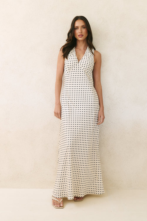 Woman wearing a long black and white patterned dress against a plain background