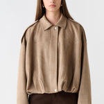 Woman wearing a beige jacket and brown pants on a white background
