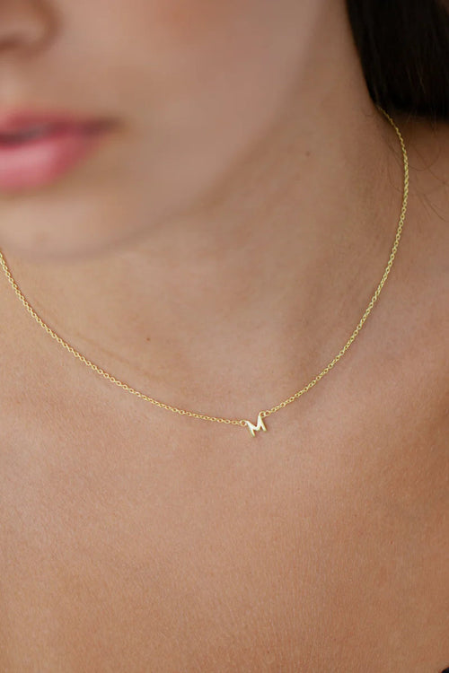 woman wearing gold necklace with initial