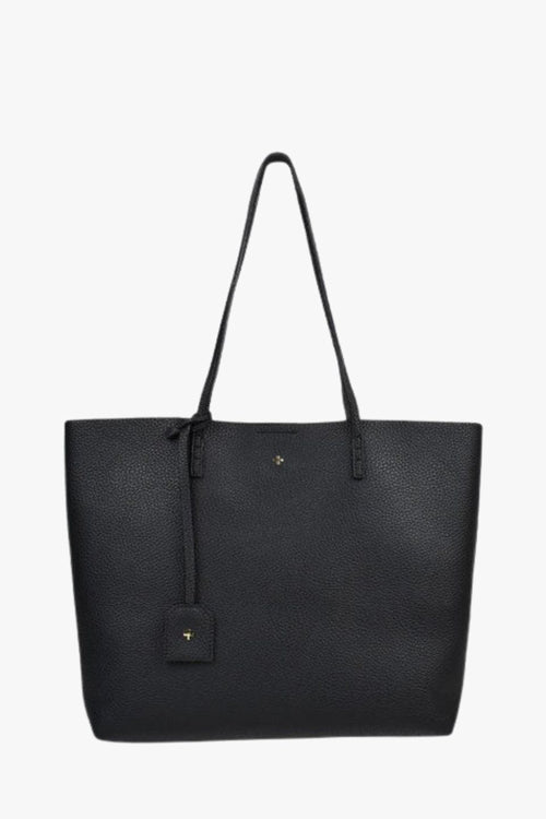 A black pebbled leather tote bag with dual shoulder straps, a hanging leather tag, and a small gold logo emblem on the front, shown against a plain white background.