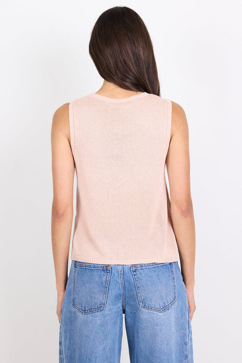 Woman wearing a light pink sleeveless top and blue jeans on a white background