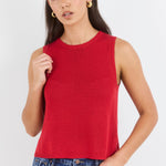 Woman wearing a red sleeveless top and blue jeans on a white background