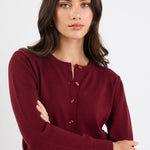 Woman wearing a burgundy cardigan with a plain background