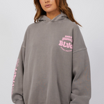 model wearing grey hoodie with pink lettering and blue jeans