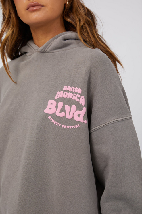 model wearing grey hoodie with pink lettering and blue jeans