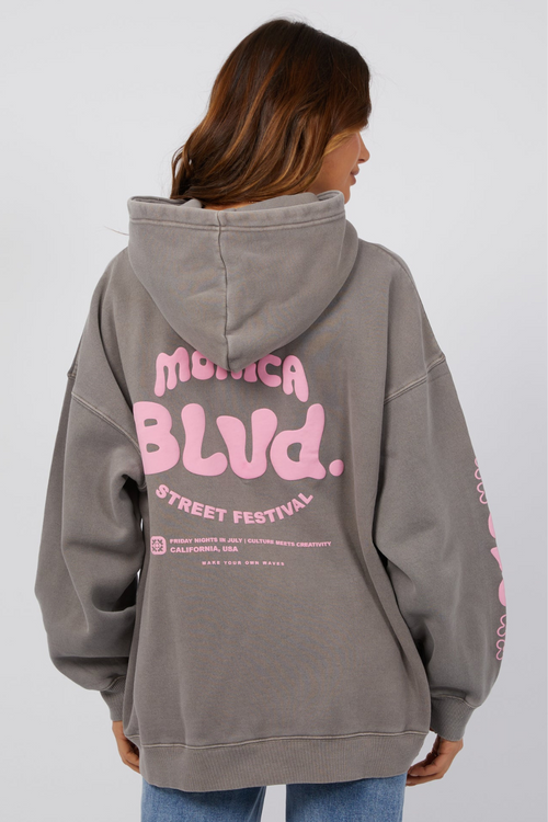 model wearing grey hoodie with pink lettering and blue jeans