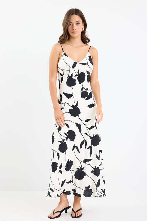 A strappy ivory dress with a bold black floral print, featuring a bias-cut design and fully lined interior. Made from 80% Viscose and 20% Nylon for a soft, breathable feel.