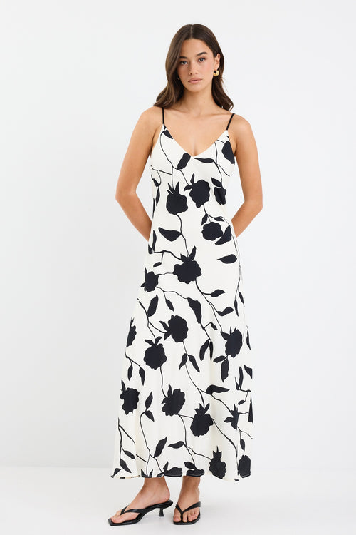 A strappy ivory dress with a bold black floral print, featuring a bias-cut design and fully lined interior. Made from 80% Viscose and 20% Nylon for a soft, breathable feel.