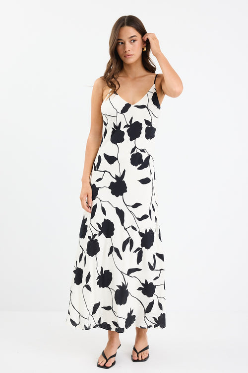A strappy ivory dress with a bold black floral print, featuring a bias-cut design and fully lined interior. Made from 80% Viscose and 20% Nylon for a soft, breathable feel.