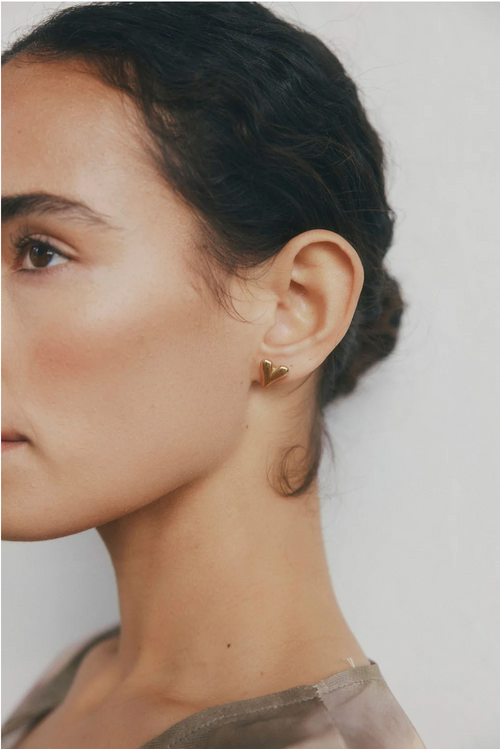 A pair of polished gold-toned heart-shaped stud earrings with a fluid, curved design and a slightly elongated point, giving a modern, sculptural look.