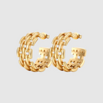A pair of gold-toned hoop earrings featuring an intricate woven-link design, creating a bold, structured look with a glossy finish and open-back detail