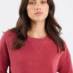 Woman wearing a red sweatshirt with 'Re:union' text on a white background