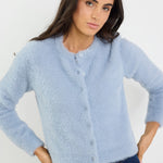 Woman wearing a light blue cardigan against a white background