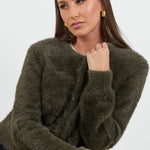 Woman wearing a green fuzzy sweater against a white background