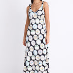 A black dress with a quirky dinner plate print, featuring strappy sleeves, a tie-back detail, and a flattering bias-cut design. Fully lined for comfort, made from a breathable viscose-nylon blend.