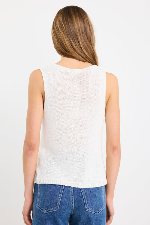 Woman wearing an ivory sleeveless knit vest top with a V-neckline, styled casually with blue jeans.