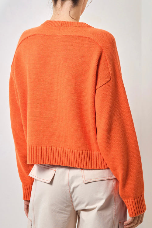 Model wears an orange knit 