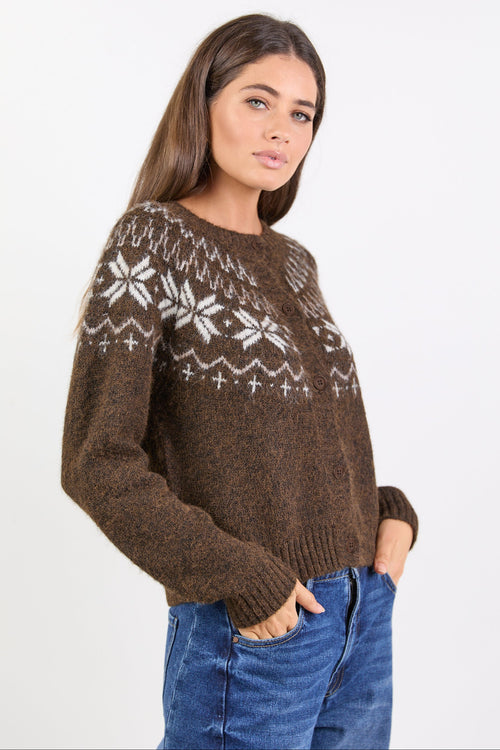 Woman wearing a brown knitted cardigan with white patterns on a plain background