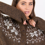 Woman wearing a brown knitted cardigan with white patterns on a plain background