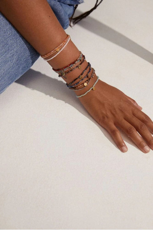 Hand wearing multiple bracelets on a light background