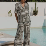 Woman wearing a short-sleeve shirt with an abstract olive and cream geometric print and button front,