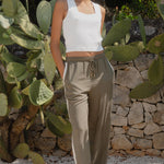 Woman wearing khaki wide-leg drawstring pants with an elastic waist, featuring a relaxed fit and side stripe detail, styled with a plain white tee 