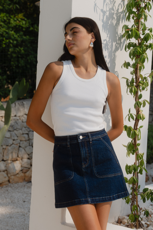 model wearing denim skirt and white tank in the sun