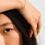 Close-up of a person with a silver bracelet on a plain background