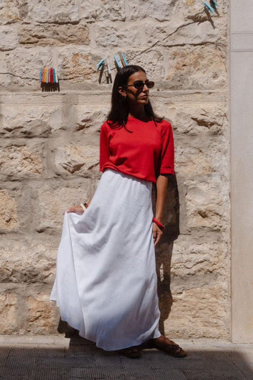 model wears a red knit t-shirt with white linen skirt