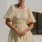 Woman wearing a short butter-yellow mini dress with puff sleeves
