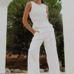 Woman wearing white pants and white top with gold accessories