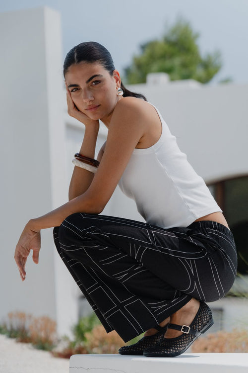 model wears a black wide leg pant with a white tank top