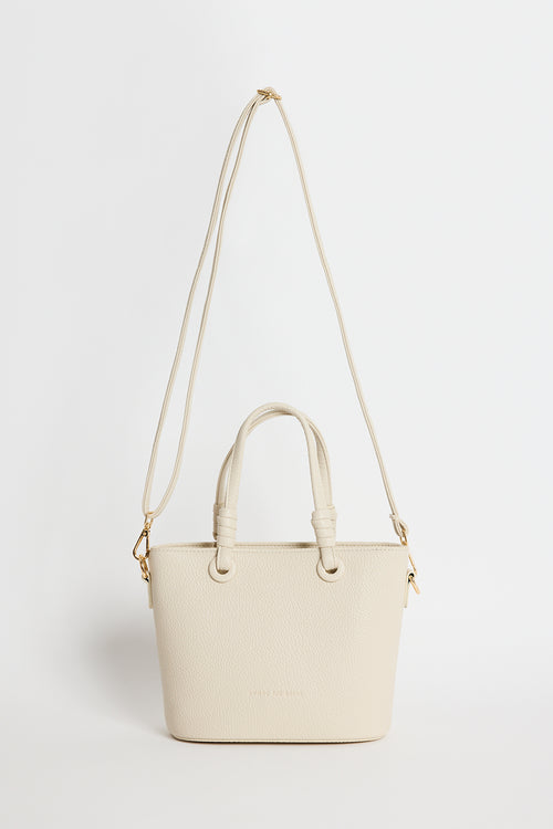 Beige PU leather mini handbag with knotted top handles and a long detachable shoulder strap, photographed against a plain light background.