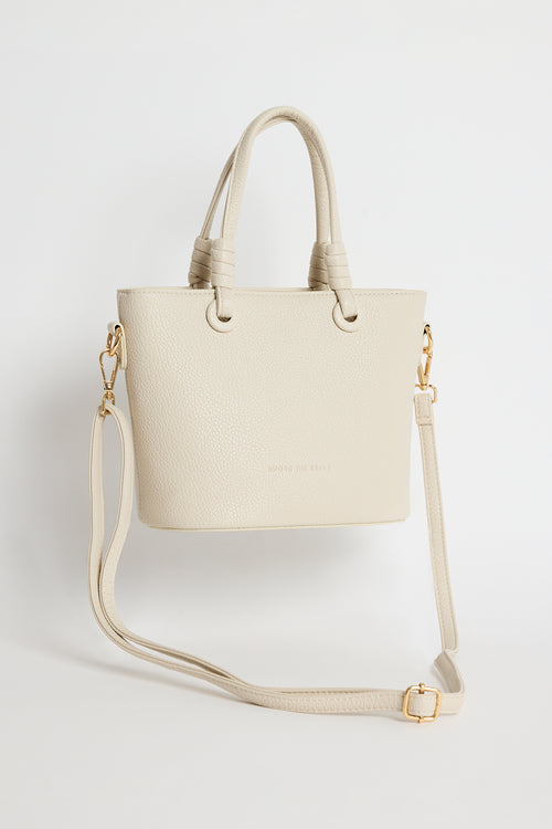 Beige PU leather mini handbag with knotted top handles and a long detachable shoulder strap, photographed against a plain light background.