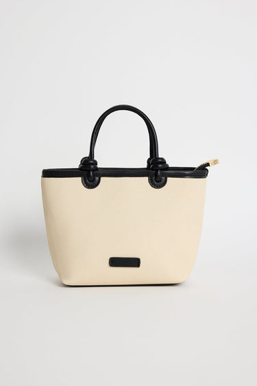 Natural canvas mini handbag with black PU trim, small knotted top handles and a long detachable shoulder strap, photographed against a plain background