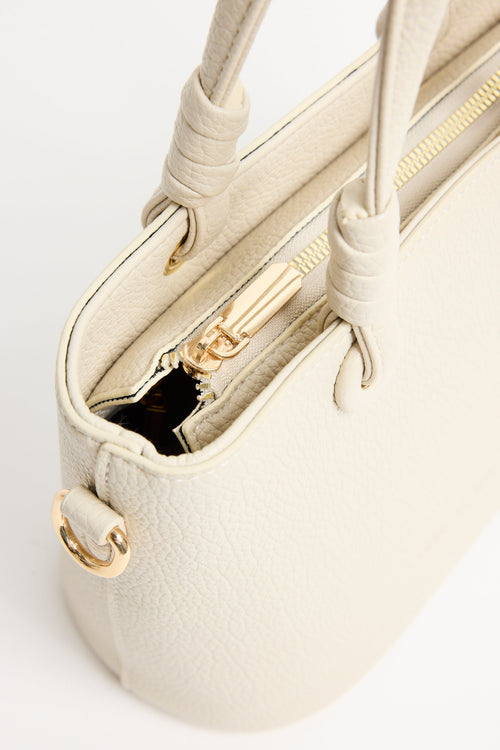 Beige PU leather mini handbag with knotted top handles and a long detachable shoulder strap, photographed against a plain light background.