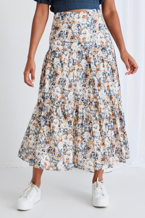 model wears a blue top with a floral maxi skirt