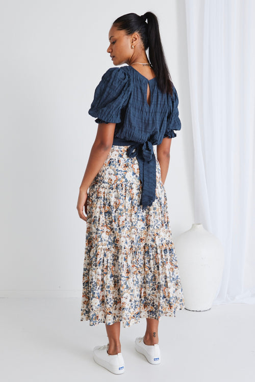 model wears a blue top with a floral maxi skirt