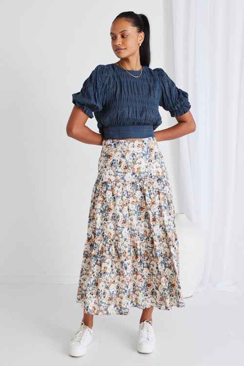 model wears a blue top with a floral maxi skirt