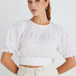 model wears a white shirred cotton top. 