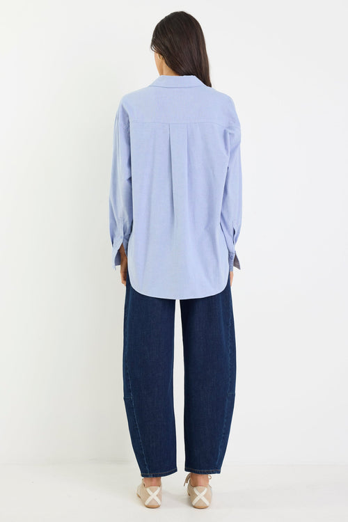 Person wearing a light blue shirt and dark blue pants on a white background