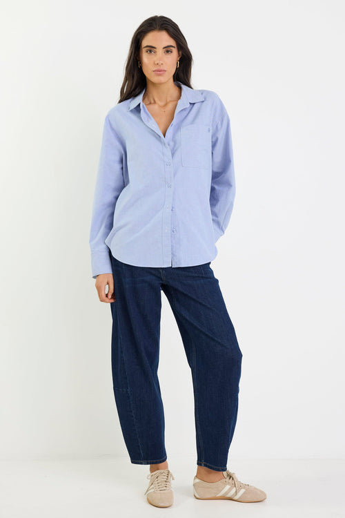 Woman wearing a light blue shirt and navy pants on a white background