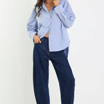 Woman wearing a light blue shirt and dark blue pants on a white background