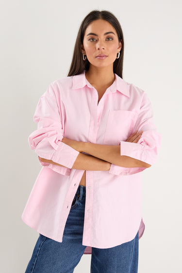 model wears a pink oversized shirt with blue jeans