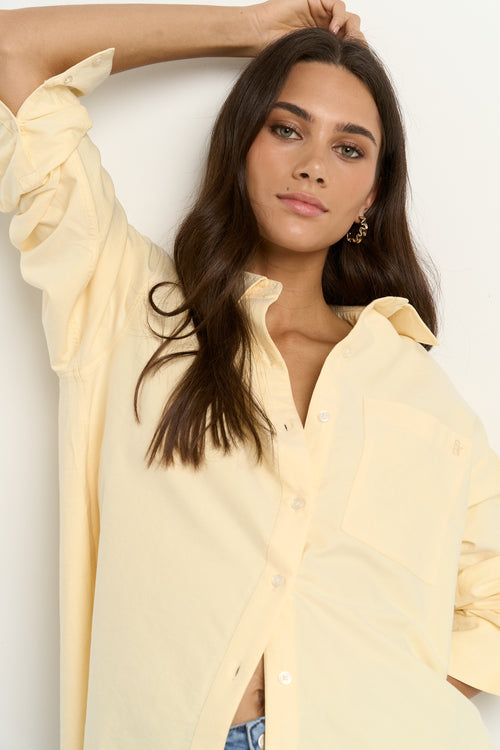 Woman wearing an oversized lemon yellow button-down shirt