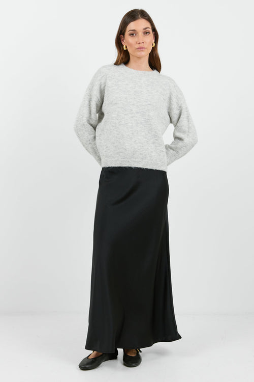 A woman wearing a light grey marle jumper with a relaxed fit and long sleeves. The sweater has a soft, cozy texture and a round neckline.