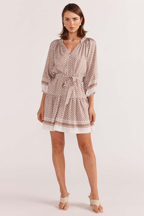 model wears a beige pattern smock mini dress