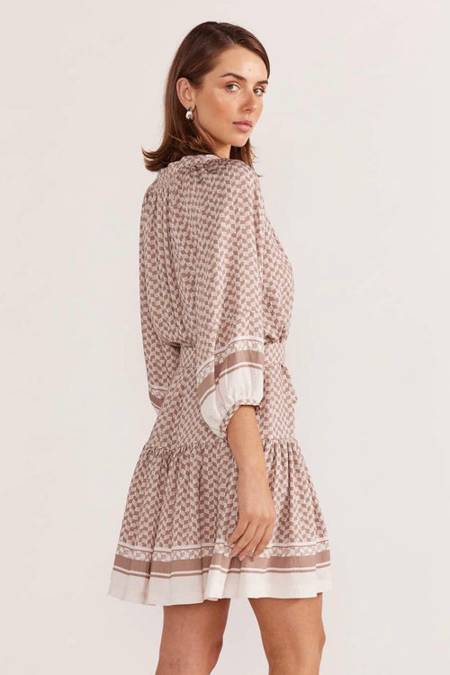 model wears a beige pattern smock mini dress