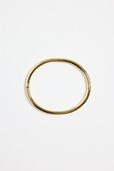 minimalist gold-plated bangle with polished finish and subtle clasp, photographed flat on a white background