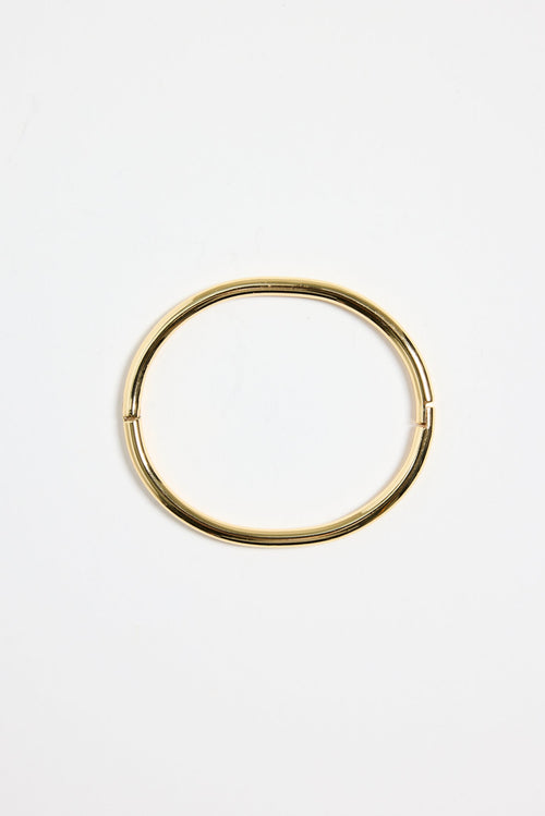 minimalist gold-plated bangle with polished finish and subtle clasp, photographed flat on a white background